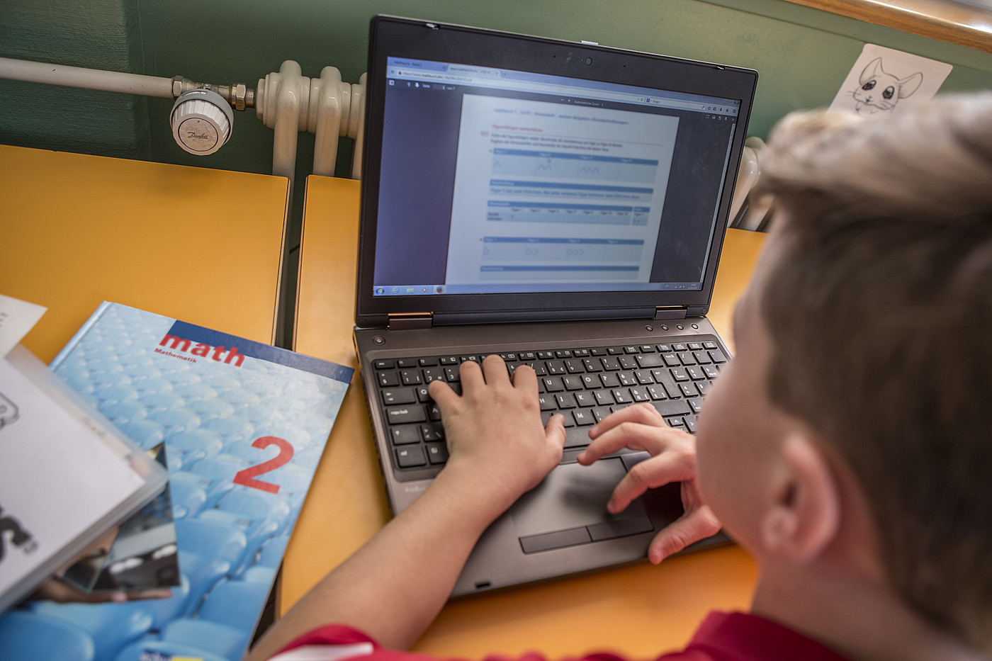Ein Junge löst Math Aufgaben auf dem Laptop.