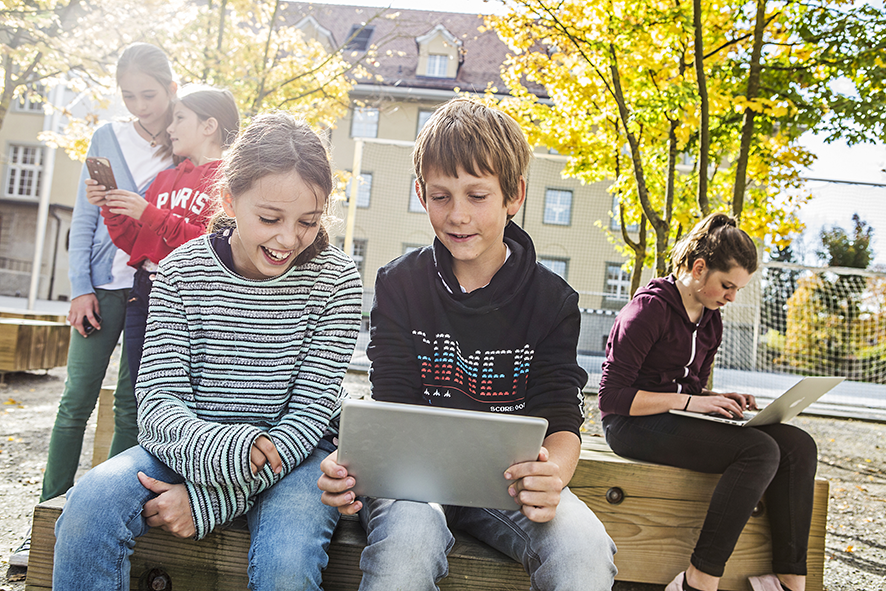 Die Schüler benützen die mobilen Geräte auf dem Schulhof.