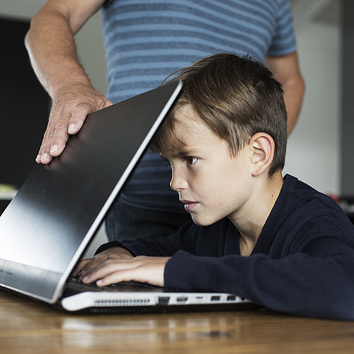 Ein Junge ist auf den Bildschirm fokussiert und kann den Laptop nicht abgeben.