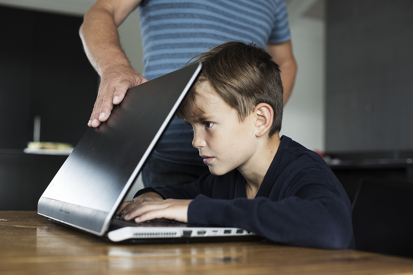 Ein Junge ist auf den Bildschirm fokussiert und kann den Laptop nicht abgeben.