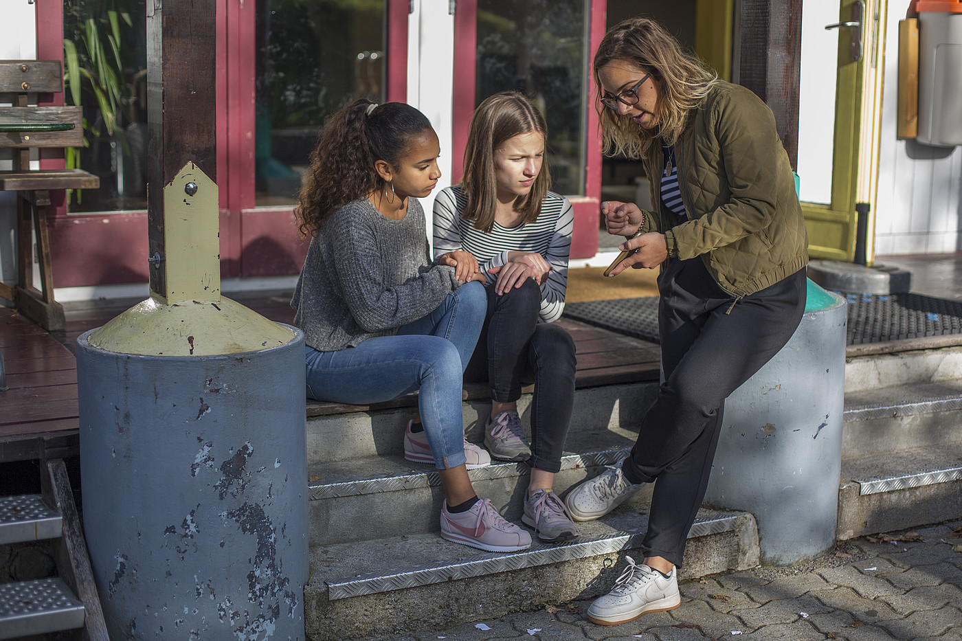 Eine Jugendarbeiterin, welche den Kindern etwas auf dem Smartphone erklärt.