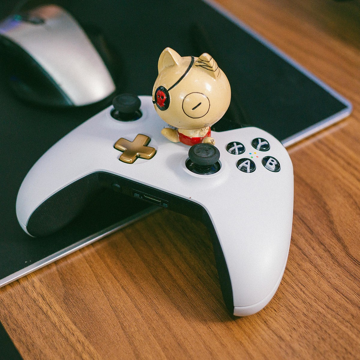 Weiss-schwarzer Gamecontroller auf einem Schreibtisch mit einer Comicfigur