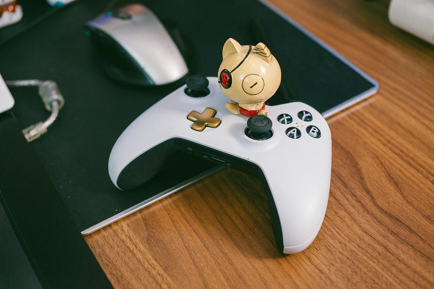 Weiss-schwarzer Gamecontroller auf einem Schreibtisch mit einer Comicfigur