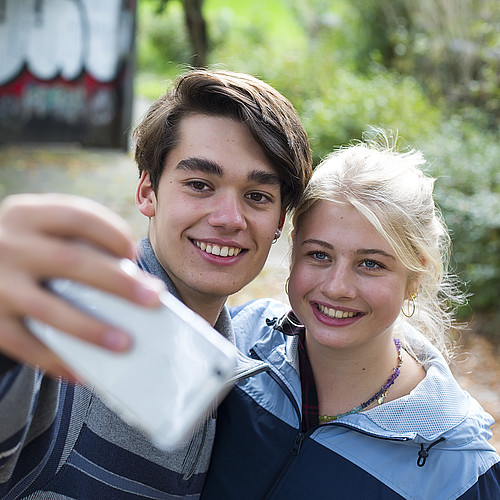 Ein Junge und ein Mädchen machen zusammen ein Foto mit dem Handy. 