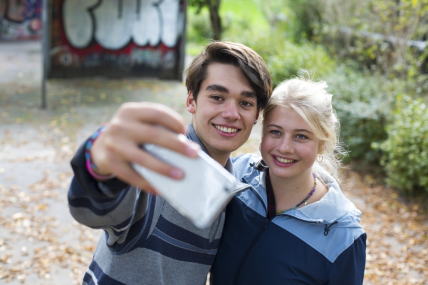 Ein Junge und ein Mädchen machen zusammen ein Foto mit dem Handy.