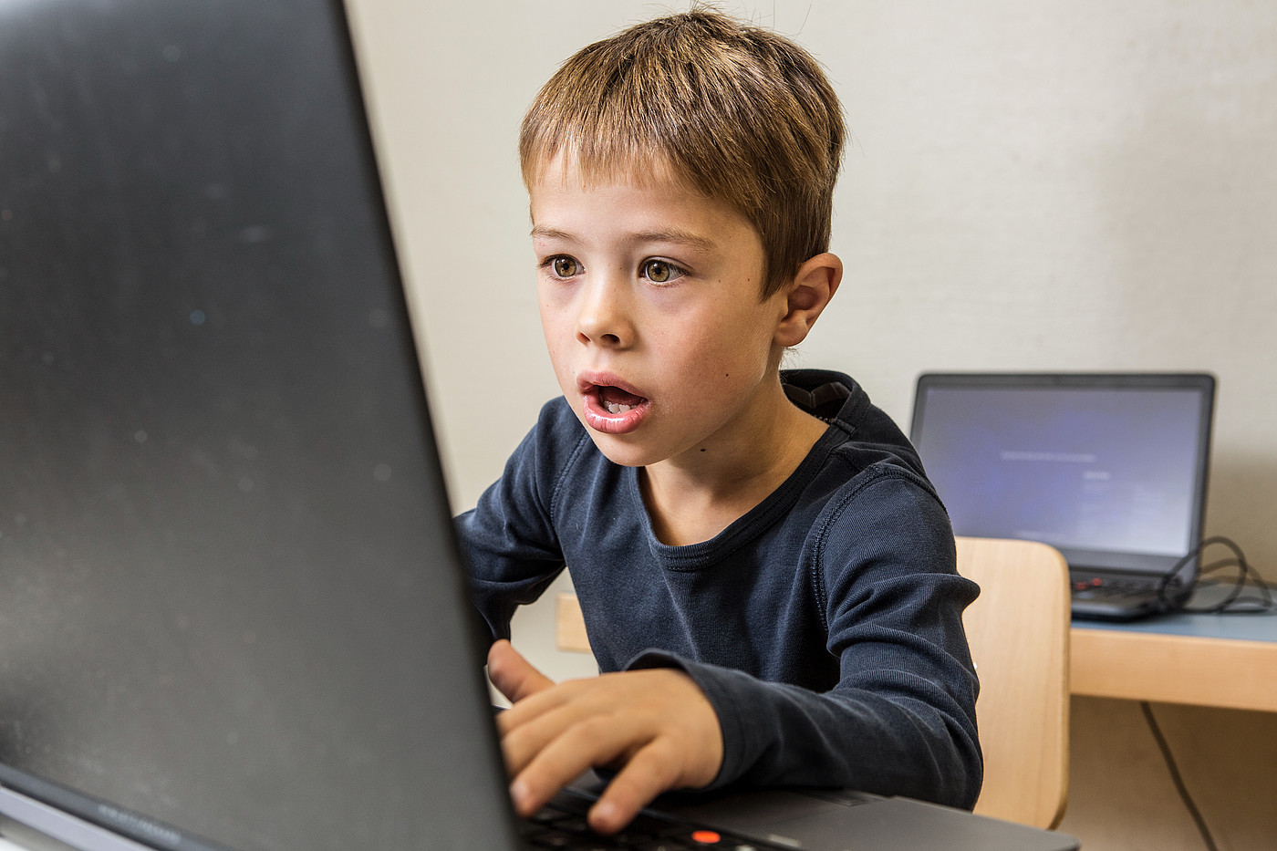 Ein kleiner Junge sieht etwas bedrohliches auf dem Laptop.