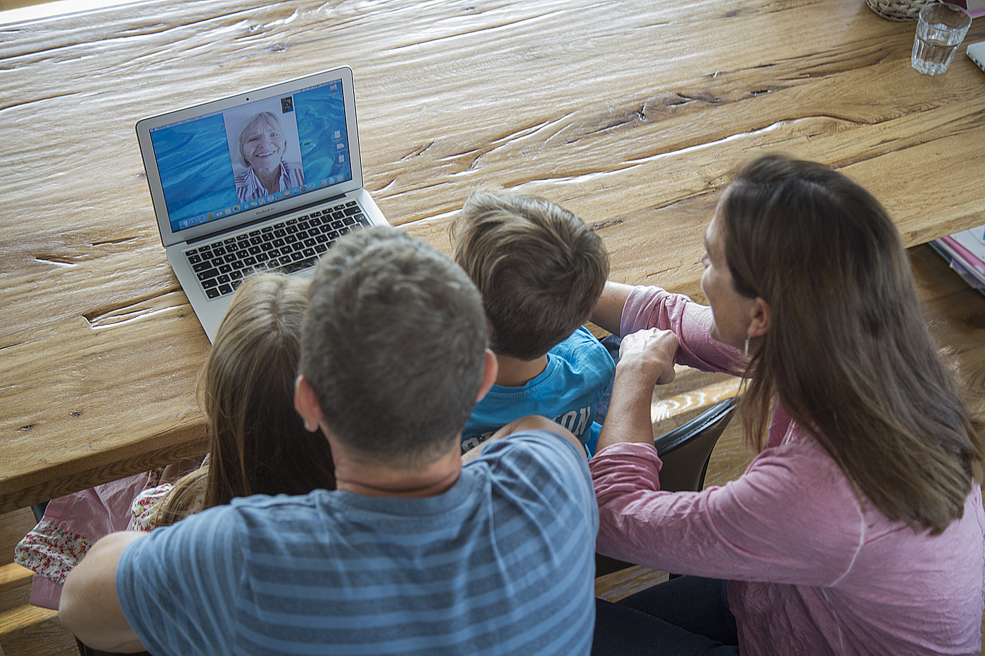 Eine vierköpfige Familie skypt mit der Grossmutter.