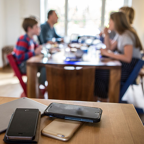 Die Smartphones liegen abseits vom Esstisch, während dem die Familie eine Mahlzeit einnimmt.