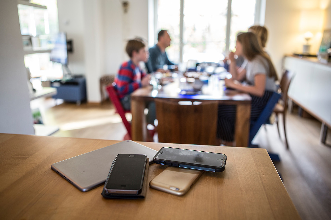 Die Smartphones liegen abseits vom Esstisch, während dem die Familie eine Mahlzeit einnimmt.