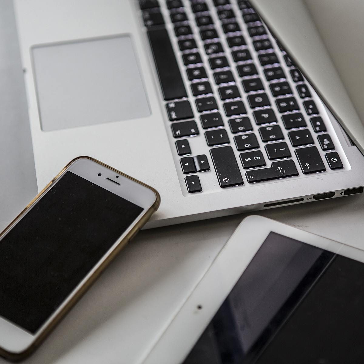 Ein Smartphone, ein Tablet und ein Laptop sind auf einem Tisch.