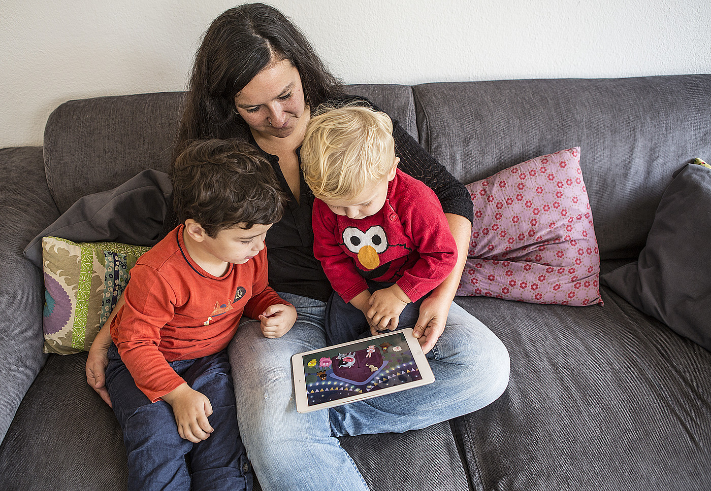 Eine Frau, die den Kindern auf dem Tablet ein Film zeigt.