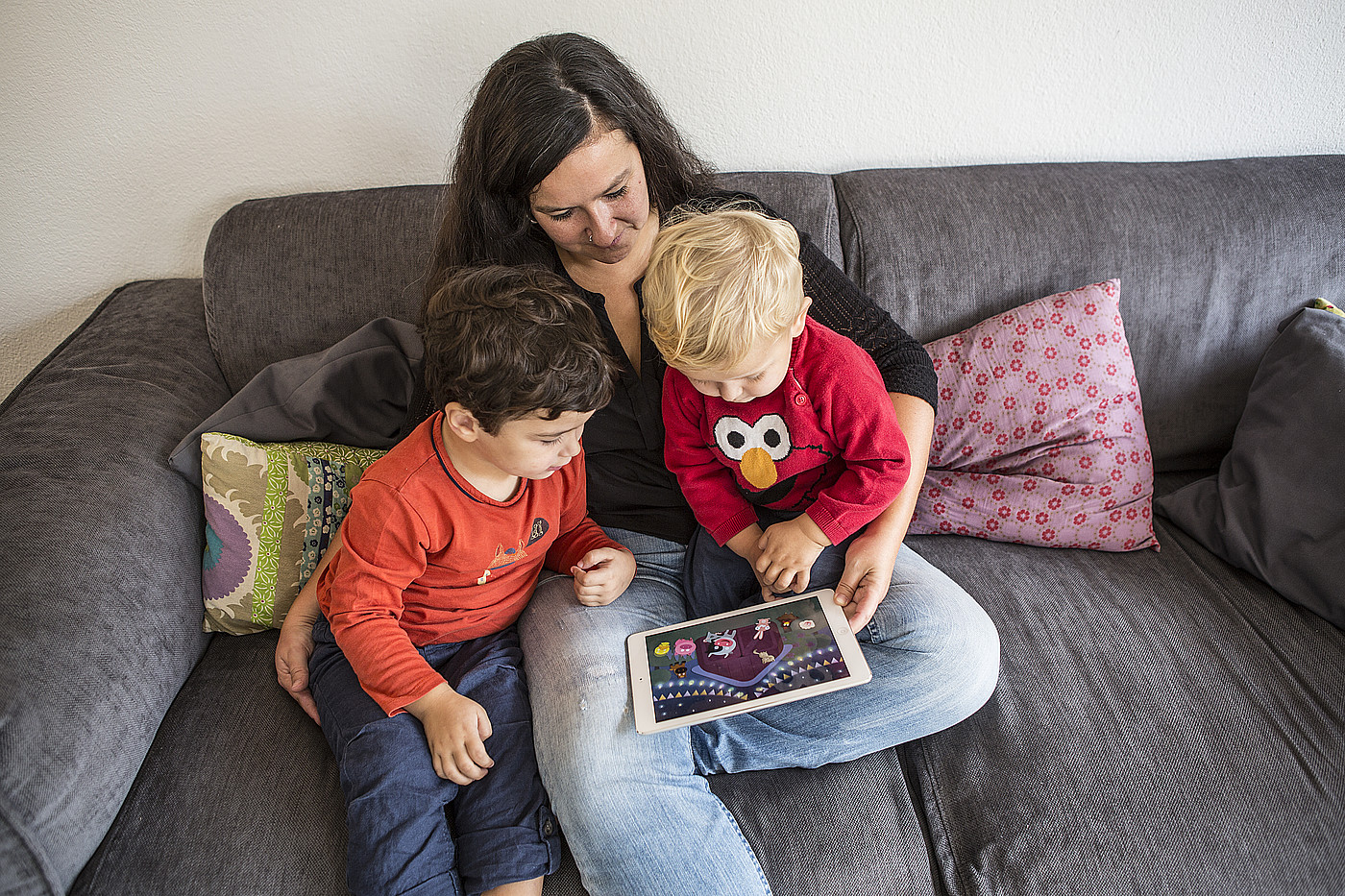Eine Frau, die den Kindern auf dem Tablet ein Film zeigt.